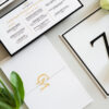 Luxury wedding menu card with gold foil typography, modern black border details, custom monogram, and coordinating table signage designed by Sherry Green Designs for planners and elegant wedding receptions