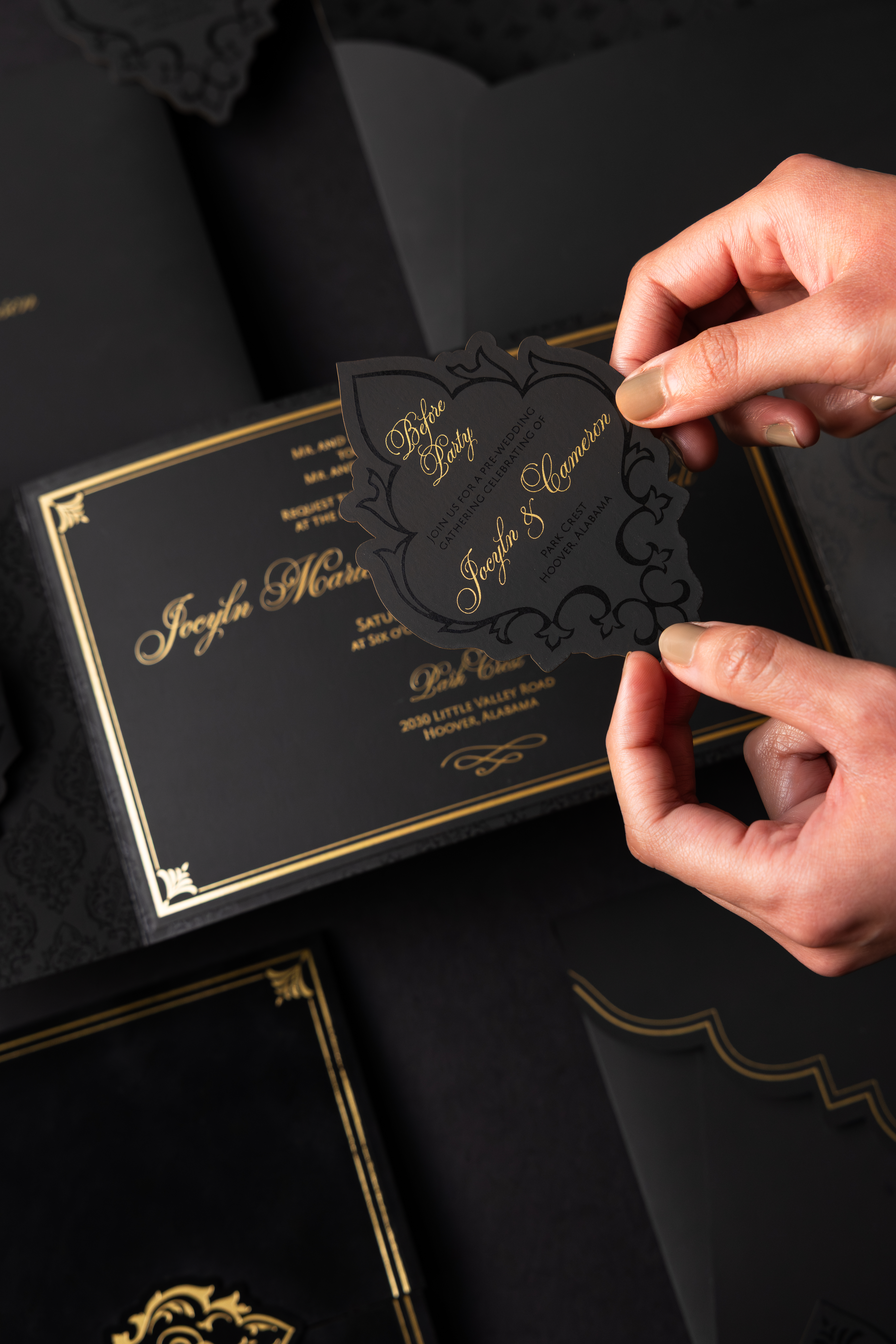 An ornate black and gold pre-wedding celebration card from a luxury wedding invitation suite featuring intricate die-cut details and elegant gold foil typography.