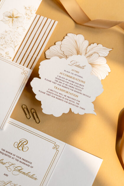 Luxury wedding invitation suite featuring gold foil details, floral-shaped accommodations card, layered inserts, and elegant black-tie wedding stationery styled with silk ribbon and refined editorial details