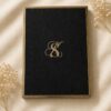 Luxury Majesté wedding invitation box featuring embossed black lace, gold foil monogram, ornate gold detailing, and an elegant keepsake presentation.