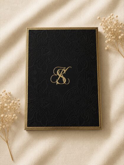 Luxury Majesté wedding invitation box featuring embossed black lace, gold foil monogram, ornate gold detailing, and an elegant keepsake presentation.