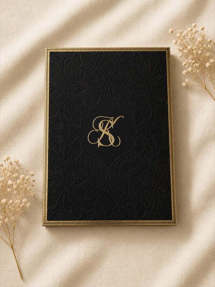 Luxury Majesté wedding invitation box featuring embossed black lace, gold foil monogram, ornate gold detailing, and an elegant keepsake presentation.