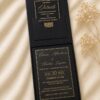 Luxury black wedding invitation box featuring a gold foil invitation card, matching details card in a black pocket, and premium presentation box displayed on an ivory fabric backdrop.