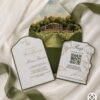 Luxury vineyard wedding invitation with gold foil lettering, embossed grapevine details, and a custom die-cut shape layered on deep green cardstock.